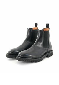 Bottes Chelsea en cuir noir avec panneaux élastiques latéraux, semelle en caoutchouc noir texturée et intérieur contrastant couleur tan. Bout arrondi et languettes de tirage.
