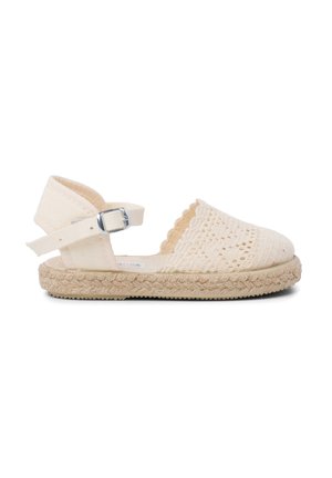Sandalia espadrille beige con parte superior tejida tipo encaje, bordes ondulados y punta redondeada. Cuenta con plataforma de yute beige y correa de tobillo con hebilla.