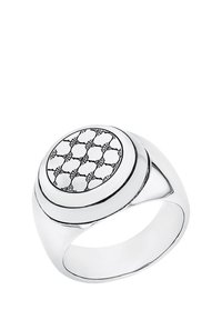 Anillo de plata con una parte superior redonda y decorada que presenta un diseño geométrico negro sobre un fondo blanco y una banda lisa y pulida.