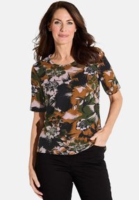 Bloemrijke t-shirt met korte mouwen, gekenmerkt door een multicolor patroon in bruin, groen en roze. Ronde halslijn en zachte stof. In combinatie met zwarte broek.