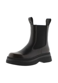 Botín Chelsea negro hecho de cuero liso con una suela de goma texturada y gruesa. Presenta paneles laterales elásticos y lengüetas para ponerlo y quitarlo con facilidad.