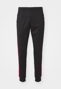 Svarta mjukisbyxor med röda sidoremmar, med elastisk midjeband och grön logotypdetalj. Tillverkade av mjukt, stretchigt tyg.
