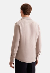 Licht beige langarmshirt van gestructureerde stof, met een puntkraag en knoopmanchetten, en een gebogen zoom.