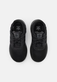 Black athletic shoes with mesh and synthetic upper, round toe, lace-up front, three striped accents, and branded tongue.