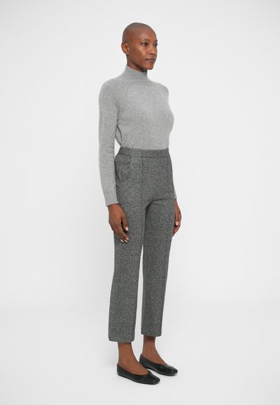 Pull gris à col haut associé à un pantalon gris texturé. Des chaussures plates noires complètent l'ensemble. Design simple, silhouette ajustée.