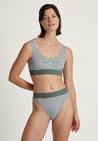 Randig bikini-set som består av en crop top med breda remmar och högmidjade underdelar. Färgerna inkluderar vitt och grönt, med en mjuk textur.