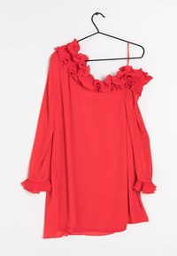 Blusa rossa off-shoulder con scollatura e polsini arricciati, realizzata in tessuto leggero, presenta maniche lunghe e un design fluido.