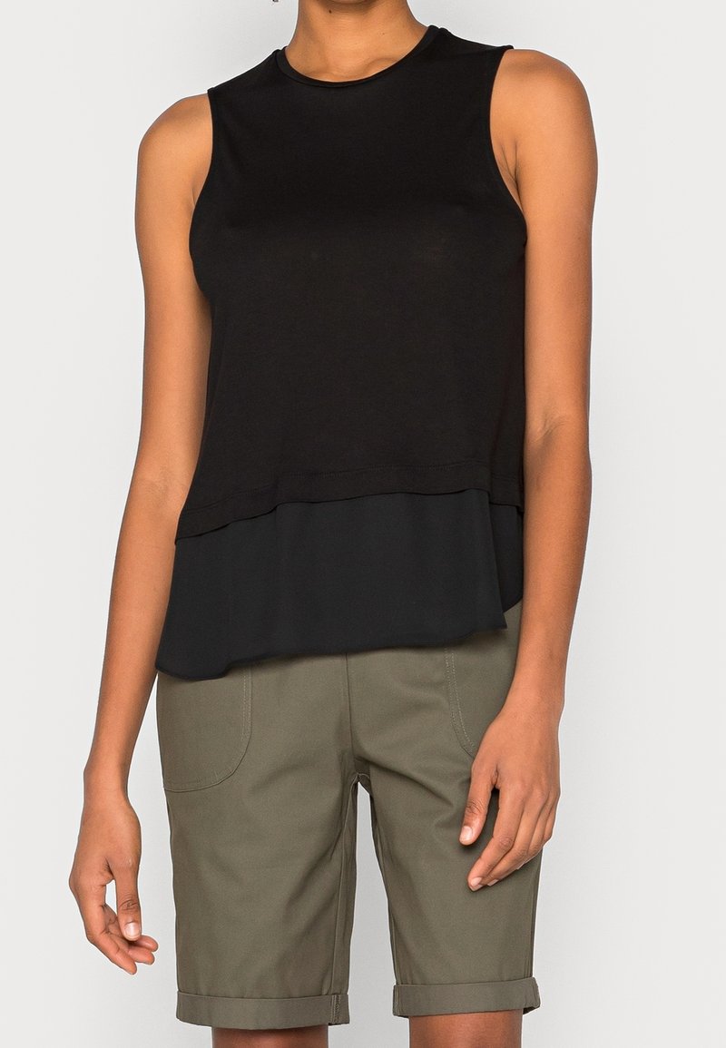 Černý bezramínkový top s texturovanou vrstvou na spodní části. V kombinaci s olivově zelenými šortkami s ohrnutými manžetami a předními kapsami.
