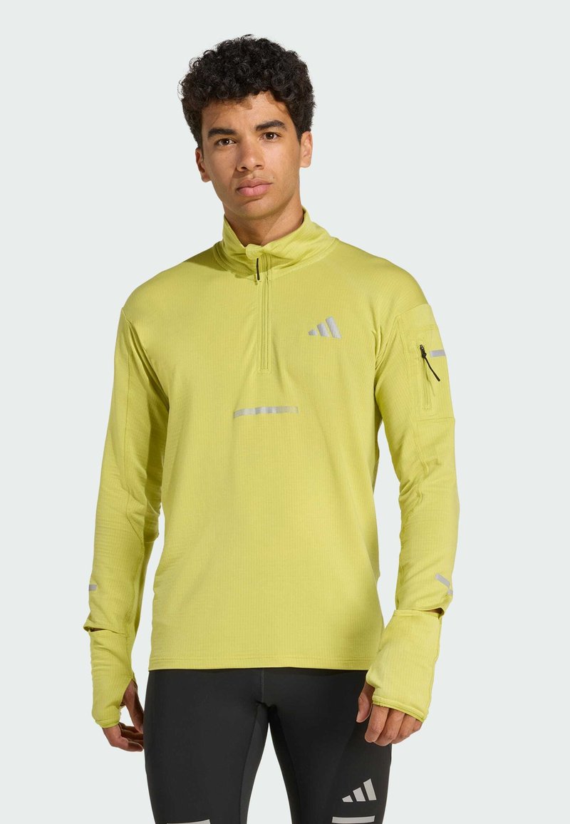 Lysegul langærmet atletisk top med halv-zip krave, reflekterende detaljer, tekstureret stof og tommelhuller på ærmerne.