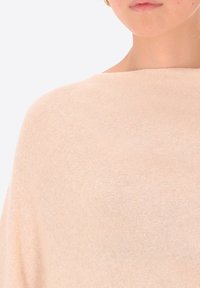 Maglione leggero color pesca chiaro in maglia, con una vestibilità ampia, caratterizzato da un ampio scollo e una texture morbida. Nessun motivo o decorazione visibile.