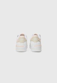 Baskets Nike blanches avec un dessus en cuir lisse, des accents rose pastel et beige, et une semelle en caoutchouc texturée avec un logo visible à l'arrière.