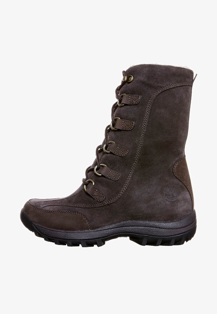 Bota alta de ante marrón con cordones en la parte delantera, ojales de metal, suela de goma y acabado texturizado. Presenta un logo en la zona del tobillo.