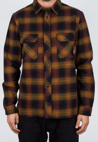 Camisa de cuadros en azul marino oscuro, naranja y amarillo mostaza. Cuenta con cuello abotonado, dos bolsillos en el pecho y una tela texturizada. Mangas largas.