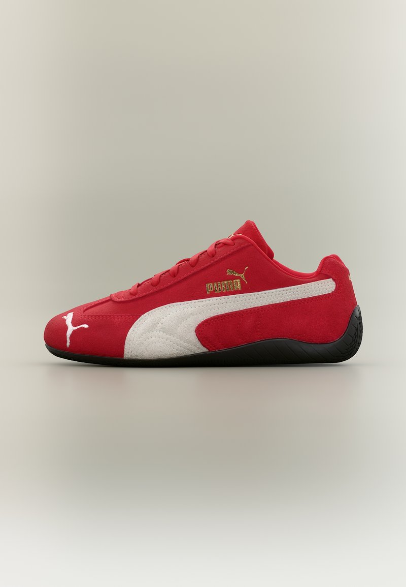 Κόκκινο αθλητικό παπούτσι Puma με λευκή ρίγα και λογότυπα, μαύρη σόλα, σχεδιασμό χαμηλού προφίλ και υφή από σουέντ, εμφανίζεται σε προφίλ πλευράς σε ουδέτερο φόντο.
