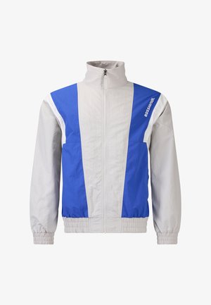 Hellgraue und blaue Windjacke mit Reißverschluss, hohem Kragen, elastischen Bündchen und "Rossignol"-Logo auf der oberen rechten Brust.