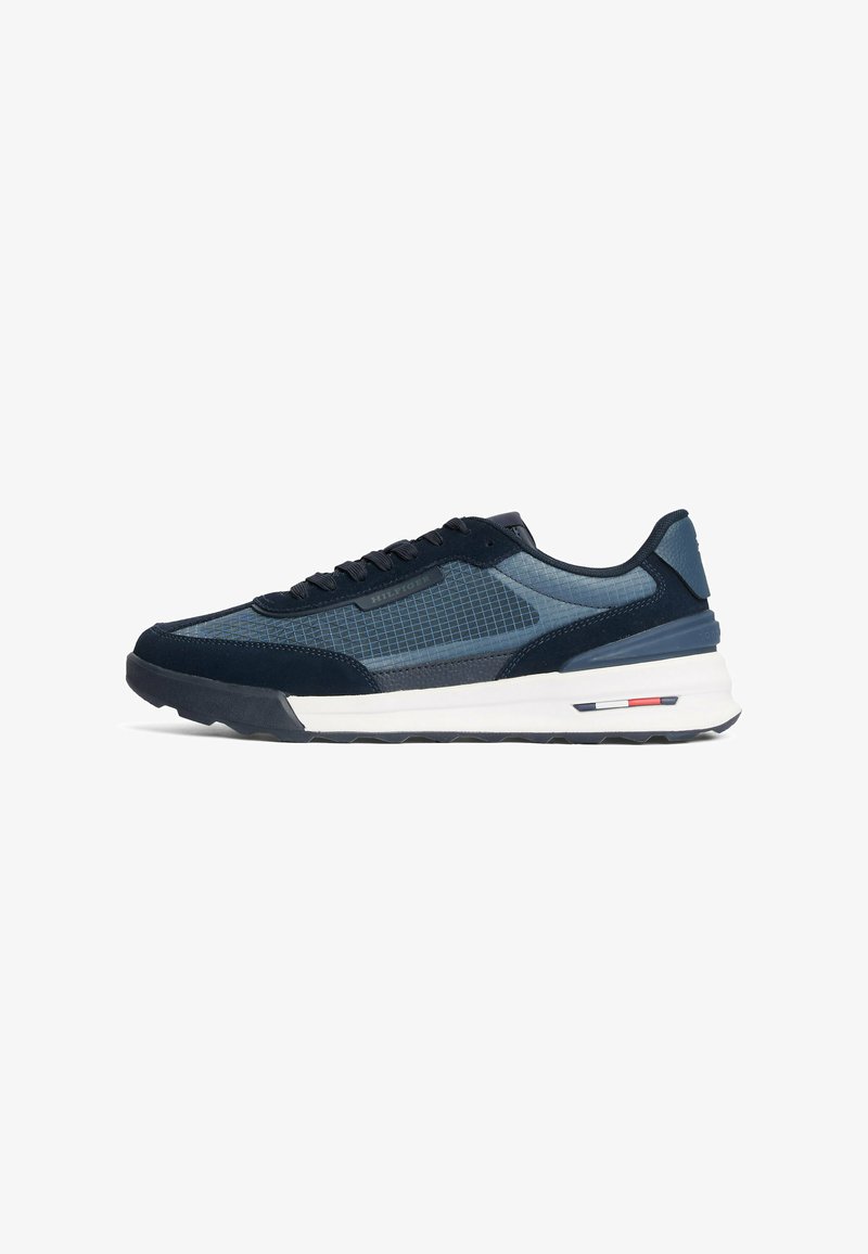Sneakers blu scuro con tomaia in rete e suede, caratterizzati da un motivo a griglia, lacci neri e una suola intermedia bianca; includono accenti rossi e blu.