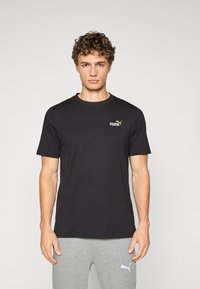 Zwarte T-shirt met korte mouwen, gemaakt van zachte stof, met een klein gouden Puma-logo op de linkerborst. Klassieke ronde halslijn en een relaxte pasvorm.