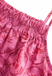 Haut en tissu rose avec un bandeau élastique froncé. Présente un motif de homard en rouge, avec un tissage texturé et de fines bretelles.