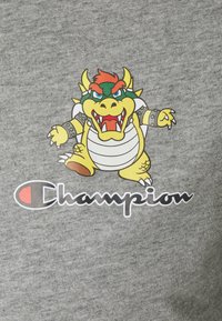 Šedá mikina s kresleným žlutým drakem, který má červené a zelené akcenty. Pod designem je černé logo "Champion".