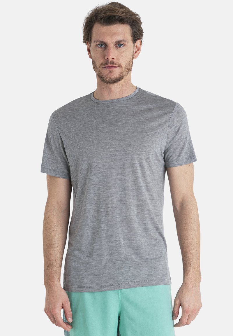 Grå kortärmad t-shirt i ett mjukt, lätt material med rund halsringning och subtil textur. Modellen bär mintgröna shorts.
