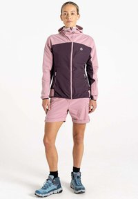 Leichte, gefütterte Jacke in Pink und Dunkelpink, kombiniert mit pinken Shorts. Mit Reißverschlusstaschen und robusten blauen Wanderschuhen.