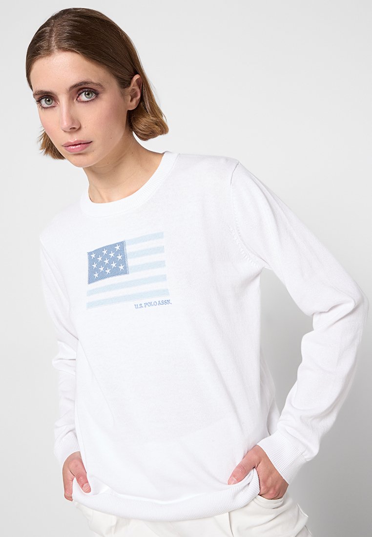 Biała bluza z kapturem z niebieskim haftowanym wzorem amerykańskiej flagi na piersi, z napisem "U.S. POLO ASSN." pod spodem. Miękka faktura materiału.