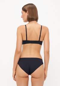 Svart bikinitsett med en enkel design, justerbare stropper og sømløst midjebånd. Materialet har en glatt tekstur.