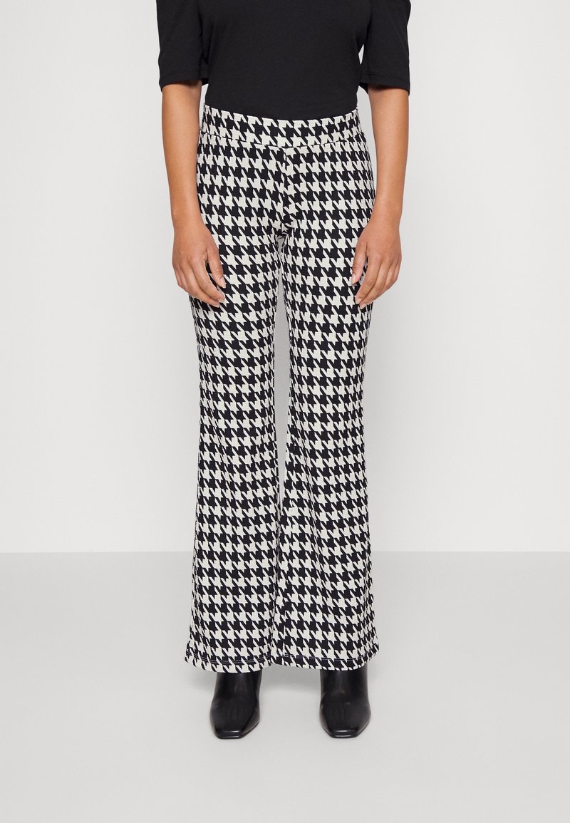 Svart och vit houndstooth-mönstrade utsvängda byxor med en slät textur, som har hög midja och en åtsittande silhuett upptill.