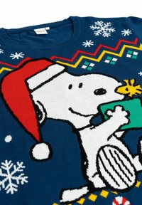 Maglione blu lavorato a maglia con una grande immagine di Snoopy in bianco, che indossa un cappello di Babbo Natale rosso e tiene un regalo verde, con motivi a fiocco di neve.
