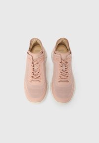 Ζευγάρι ανοιχτόχρωμα ροζ πλεκτά αθλητικά παπούτσια με μπεζ σόλες και κορδόνια, από πάνω, πάνω σε λευκό φόντο.