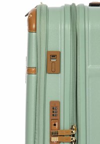 Harde koffer in mintgroen met tan accenten. Heeft een combinatie slot, USB-poorten en textuurdetail op de oppervlakte.