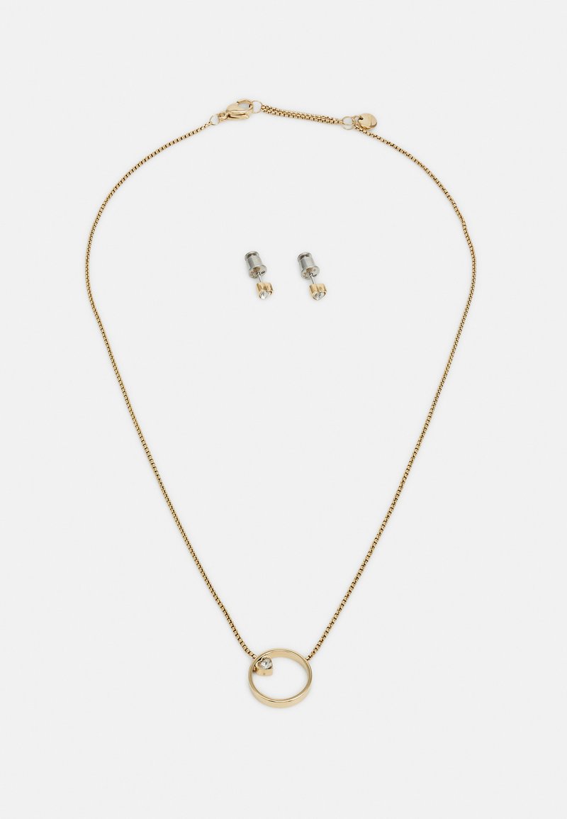 Zlatý náhrdelník s kruhovým přívěskem a malým akcentem v podobě drahokamu, doplněný o odpovídající stříbrné náušnice ve tvaru pecky.