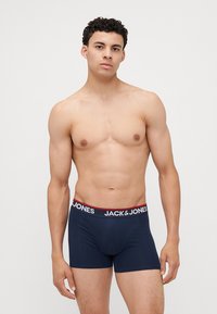 Mörkblå bomullskalsonger med en kontrasterande midja i svart och röd som har "JACK & JONES"-logotypen. Stretchig, kroppsnära design.