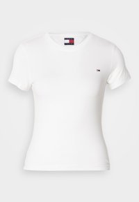 Camiseta blanca de algodón con mangas cortas, escote redondo, que presenta un pequeño logo en el pecho. Textura suave, silueta ajustada.