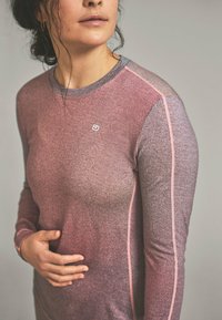 Long-sleeve athletic shirt in gradient pink and gray. Features a textured fabric, contrasting stitching, and a small logo on the chest.