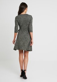 Sukienka w print w panterkę z lekkiego materiału, dopasowana w talii, rozkloszowany dół. Posiada rękawy o długości trzech ćwiartek oraz okrągły dekolt. Czarne szpilki.