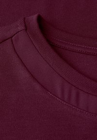 Burgundowy lekki materiał bawełniany z okrągłym rybanym dekoltem oraz gładką teksturą, zdobiony warstwowym przeszyciem wokół szyi.