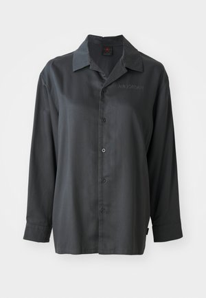 Black long-sleeve shirt, smooth fabric, button-up front, pointed collar, subtle "AIR JORDAN" embroidery on the chest, relaxed fit.