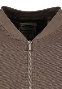 Veste zippée marron en tissu texturé, avec un col rond et une fermeture éclair en argent. L'étiquette indique la marque, le détail fait main et la taille S.