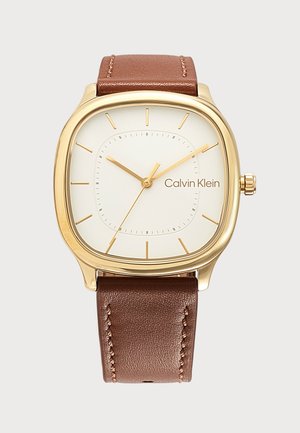Zlaté štvorcové hodinky s bielym ciferníkom, hnedým koženým remienkom, minimálnymi hodinovými značkami a logom Calvin Klein na pozícii tri hodiny.
