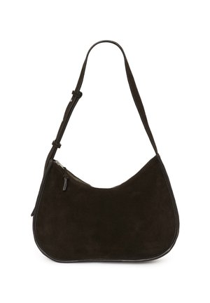 Femme portant un cardigan marron boutonné, jupe en cuir noire, bottes noires montantes jusqu'aux genoux, tenant un sac à main marron, debout devant un fond uni.