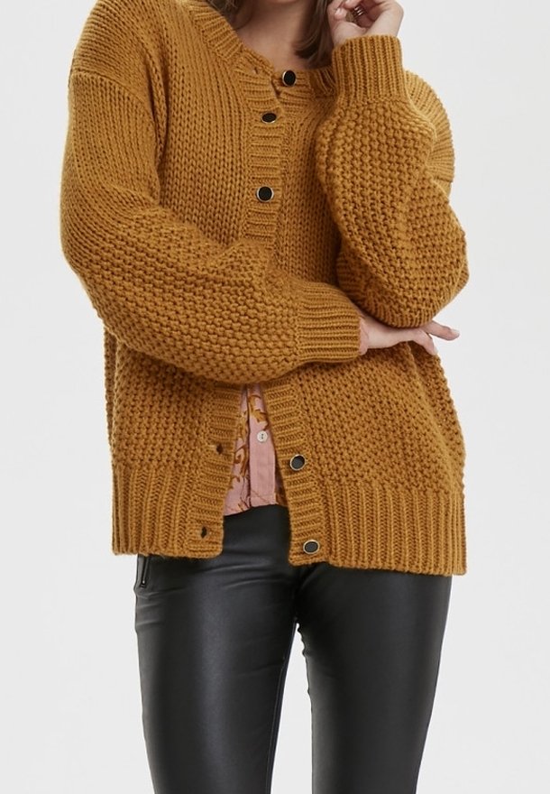 Sinapinkeltainen neulecardigan, jossa on tekstuuri kuvio, pyöreä kaula-aukko ja mustat napit, yhdistettynä vaaleanpunaiseen paitaan alla.