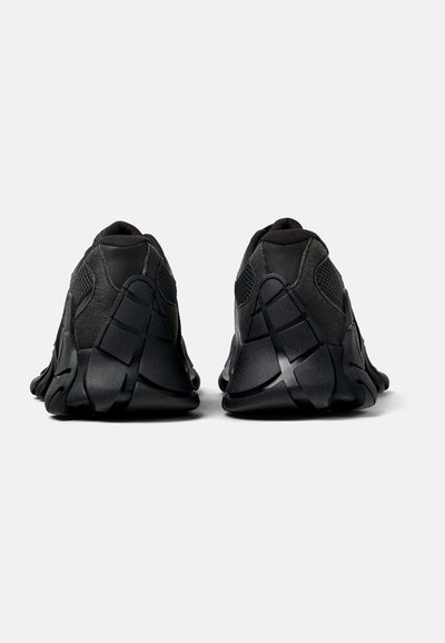 Scarpe sportive nere con un design elegante, una tomaia testurizzata, pannelli in rete morbida e una suola in gomma resistente con battistrada pronunciato.