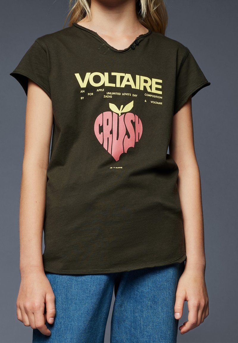 Oliveně zelené bavlněné tričko s krátkým rukávem, s stylizovaným grafickým motivem jablka a textem ve žluté a růžové barvě. Jednoduchý kulatý výstřih.