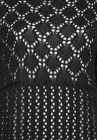 Svart stickad tyg med ett öppet, geometriskt mönster som har diamantformer och vertikala ränder, vilket skapar en texturerad look.