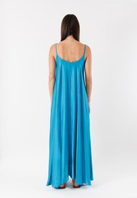 Abito maxi in satin blu con spalline sottili, silhouette fluida e design minimalista. La texture liscia e la leggera lucentezza ne esaltano l'aspetto.