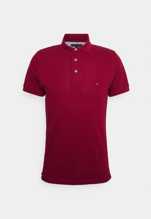 Polo à manches courtes rouge foncé pour homme avec patte de boutonnage à trois boutons et petit logo brodé sur la poitrine sur fond uni.