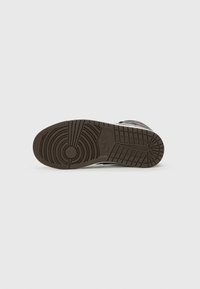 Nike potplat tenisica, smeđi gumeni materijal s kružnim i mrežastim uzorcima, teksturiran za prianjanje, s kružnim logotipom blizu pete.