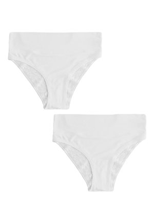 Žena nosi jednoliate biele bezšvové spodné prádlo s vysokým pásom, stojí s uvoľnenou rukou pri tele na neutrálnom pozadí.