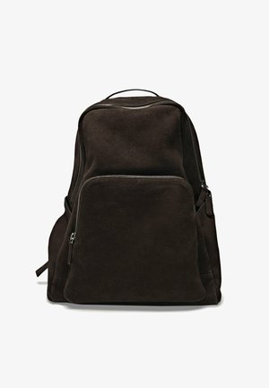 Bruine suède rugzak met een gladde textuur, voorzien van een hoofdcompartiment en een voorzak met rits. Minimalistisch ontwerp met verstelbare schouderbanden.